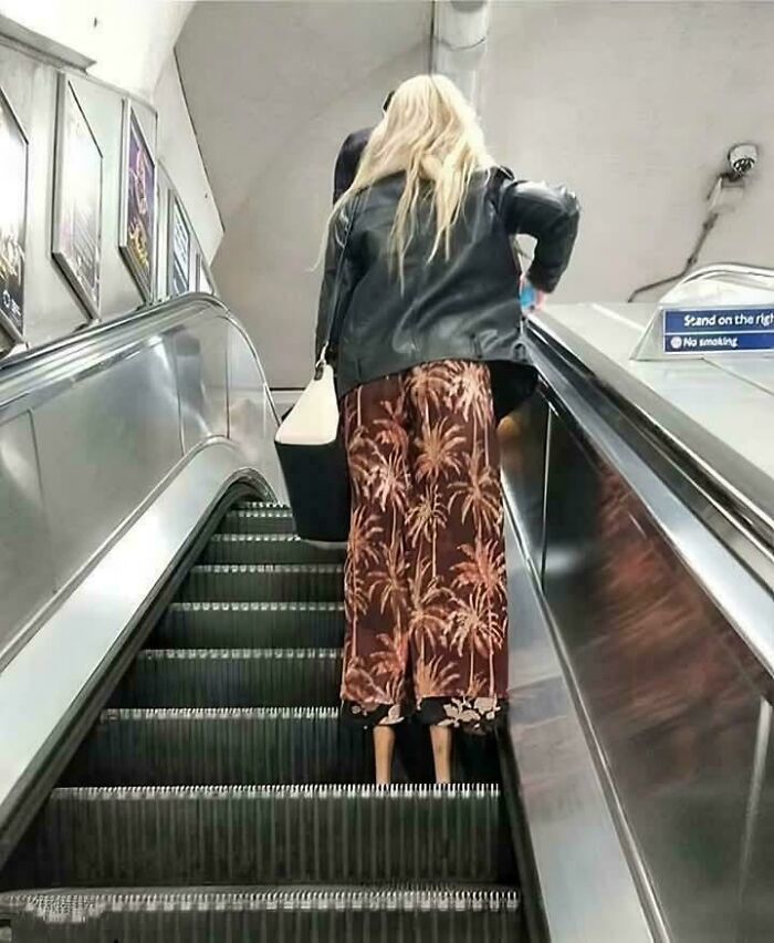 Woman with skirt and visible legs on escalator creating a confusing photo effect to challenge the brain to catch up.