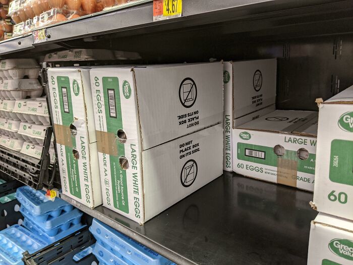 Boxes of large white eggs placed incorrectly on store shelves, showcasing poor job performance in stocking tasks.