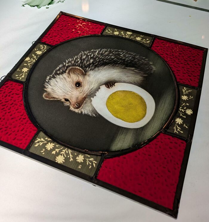 Stained glass art featuring a detailed hedgehog holding a painted egg, showcasing cool handmade creativity.