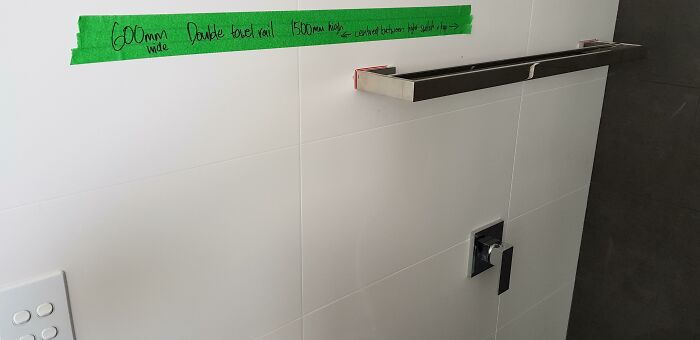 Poorly installed wall shelf with uneven measurements taped on the wall, showing a clear example of bad job e*******n.