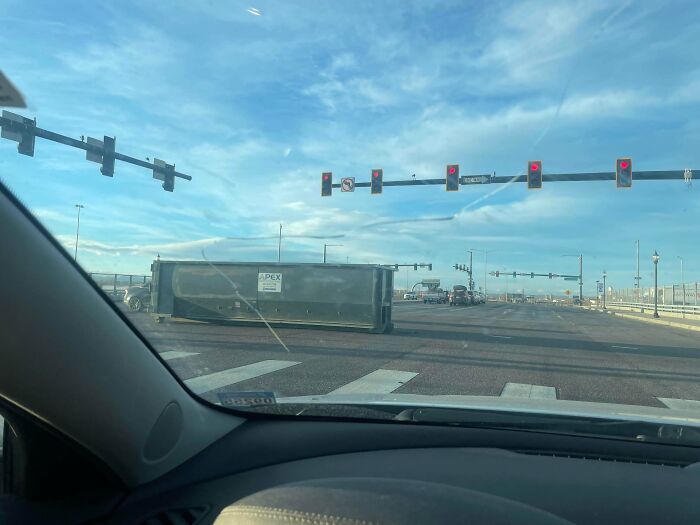 Overturned trailer blocking intersection under red lights showing a clear example of jobs done poorly and impressively bad.