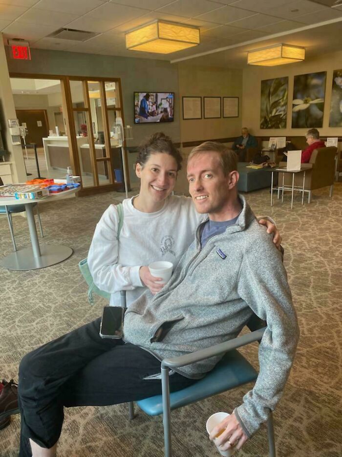 Couple sitting together in a waiting room, creating a confusing visual that may make your brain take a moment to catch up.