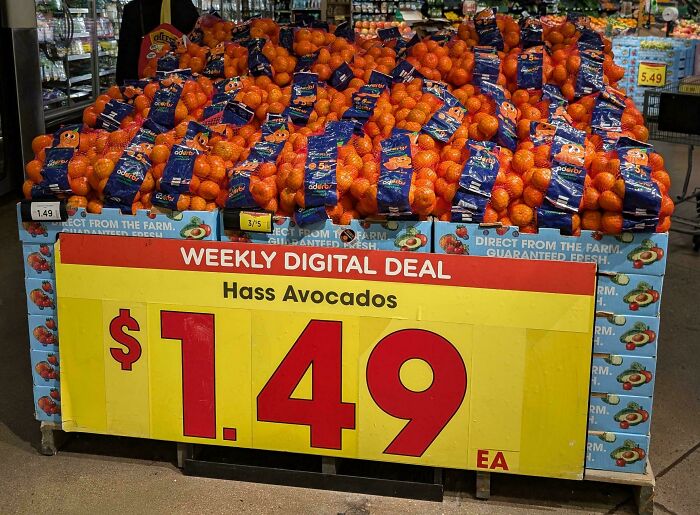 Grocery store display showing oranges labeled as Hass avocados with a wrong price sign, a job done poorly.