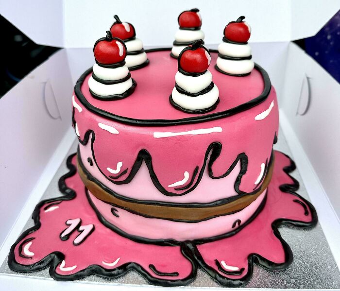 Pink masterfully crafted cake with white frosting swirls and red cherries, showcasing human creativity in cake design.