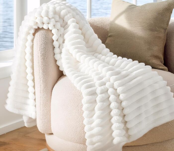 Soft white textured blanket draped over a beige chair, one of the popular products on Amazon wish lists.