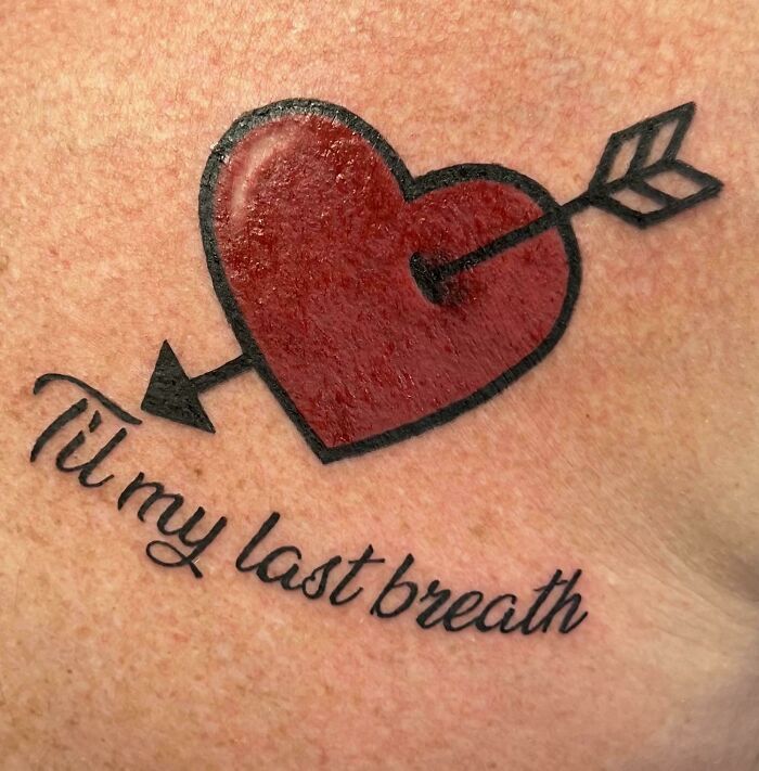 Red heart pierced by an arrow tattoo with the phrase til my last breath, showcasing wholesome tattoos with meaningful ink.