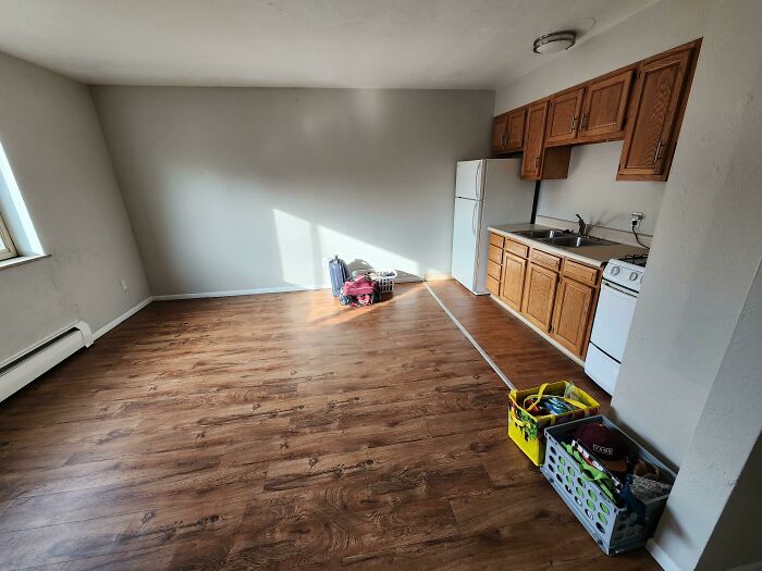 Empty apartment kitchen with wooden floors and unpacked boxes, symbolizing a leap of faith in life decisions.