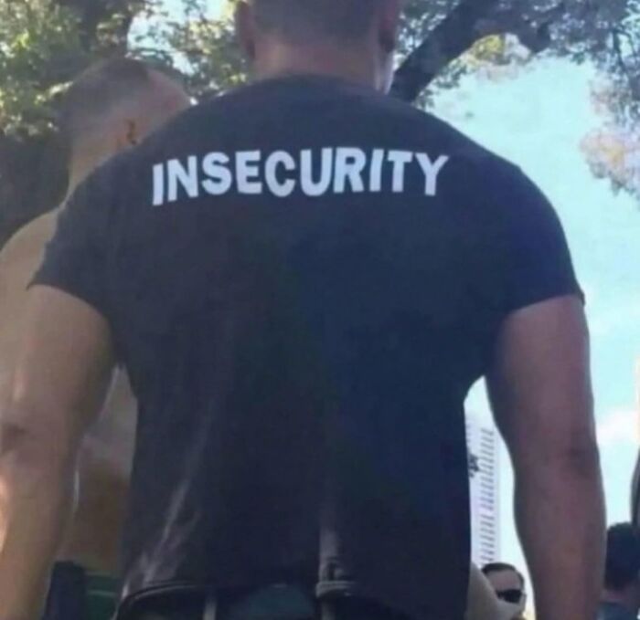 Man wearing a black shirt with the word insecurity printed on the back in a trippy picture with an outdoor background.