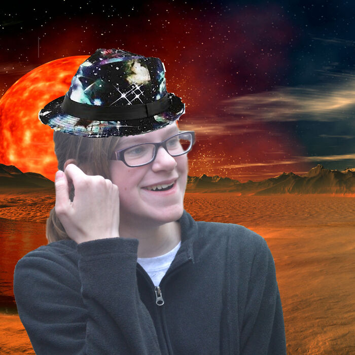 Teen wearing glasses and a galaxy-patterned fedora, smiling against a surreal red planet landscape in a childhood photo.
