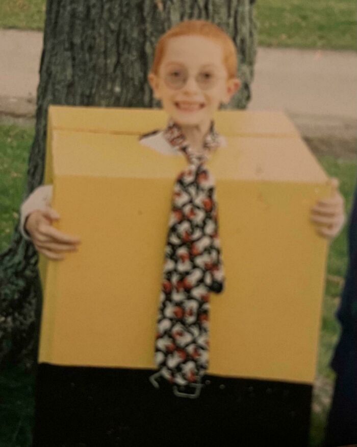 Child in a homemade costume with glasses and patterned tie, part of hilariously awkward childhood photos collection.