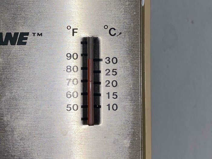 Thermometer showing temperature in Fahrenheit and Celsius on a metal surface, highlighting rental nightmares with faulty equipment.