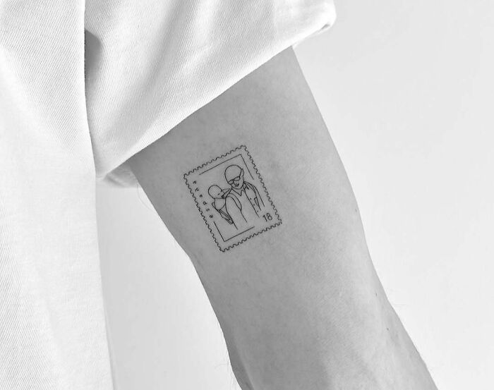 Minimalist wholesome tattoo of two people inside a postage stamp design on inner arm showing meaningful ink.