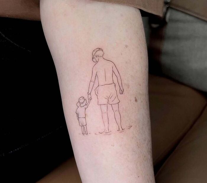 Minimalist tattoo on forearm featuring a parent and child holding hands, showcasing wholesome tattoos with deep meaning.