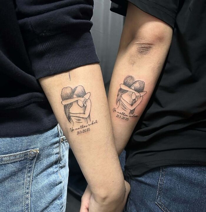 Matching wholesome tattoos of two people hugging with the phrase no matter what and a date on forearms.