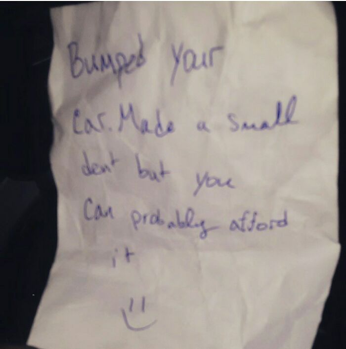 Handwritten note left on car saying sorry for a small dent and suggesting the owner can probably afford to fix it.