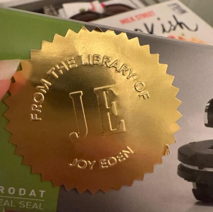 Gold embossed custom gift seal with initials JE on a book, showcasing unique custom gifts for Christmas.