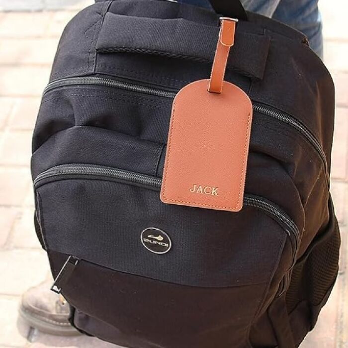 Black backpack with a personalized brown leather luggage tag featuring the name Jack, a custom gift idea for Christmas.