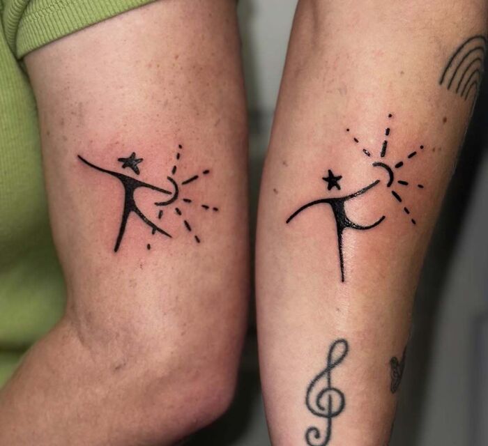 Minimalist matching tattoos on two arms, featuring abstract figures with stars and rays, showcasing wholesome tattoo meaning.