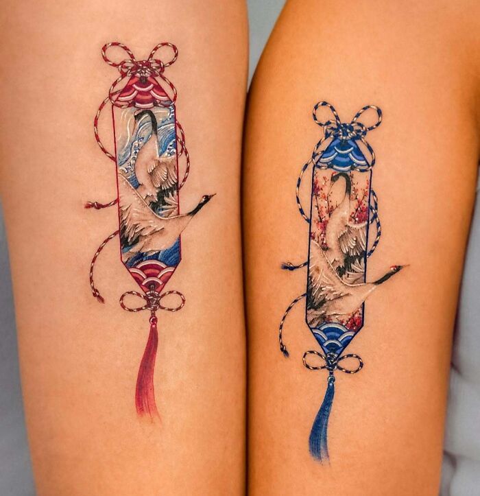 Matching colorful crane tattoos with intricate designs and ribbon details, showcasing wholesome tattoos with meaningful ink.