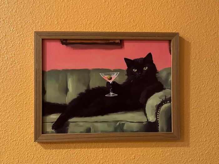 Framed painting of a black cat lounging on a green couch with a martini glass, a quirky white elephant gift idea.