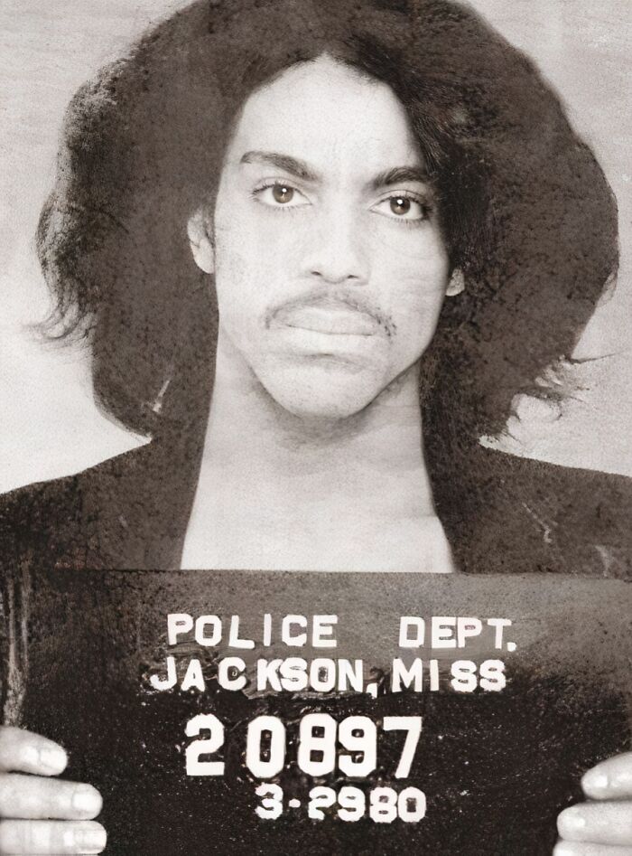 Mugshot of a celebrity taken after being arrested, showing a close-up of a young man holding a police department board.