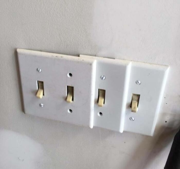 Multiple light switches installed unevenly with mismatched plates showing poor job e*******n almost impressive in craftsmanship.