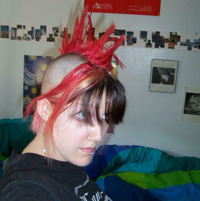 Teen with bright red spiked mohawk and piercings posing indoors, a hilarious awkward childhood photo capturing unique style.