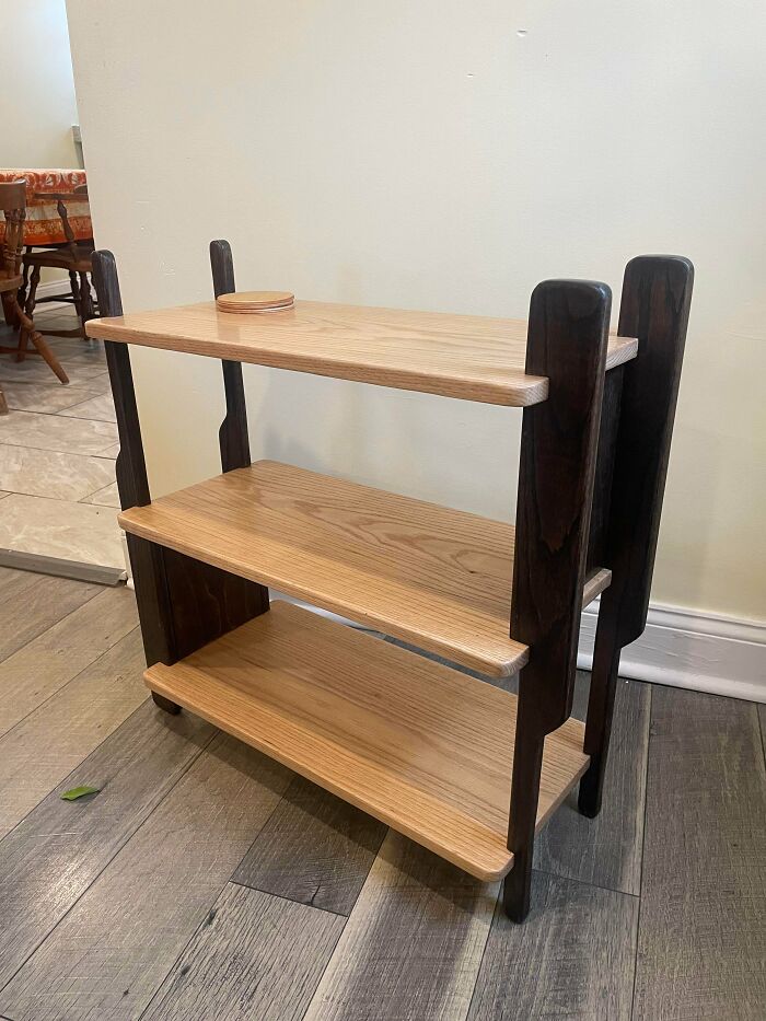 Three-tier wooden shelf with dark supports and light wood surfaces, showcasing woodworking craftsmanship and design.