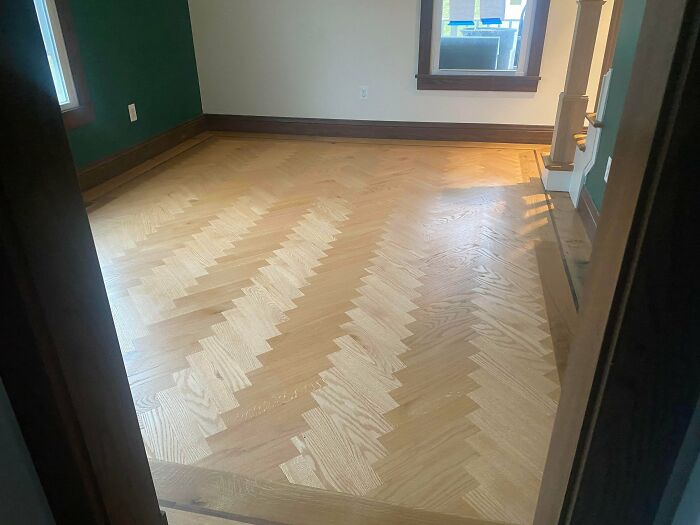 Newly crafted wood floor with intricate herringbone pattern showcasing expert woodworking skills in a bright room.