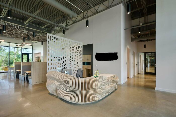 Modern office interior featuring a unique woodworker-carved reception desk with intricate layered design and open workspace.