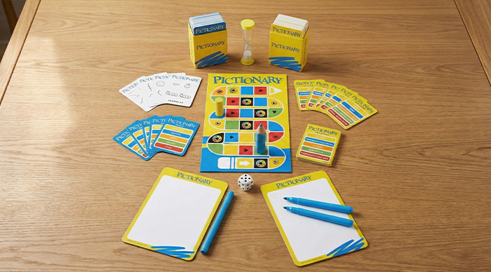 Pictionary board game setup with cards, markers, timer, and game pieces on a wooden table for party game fun.