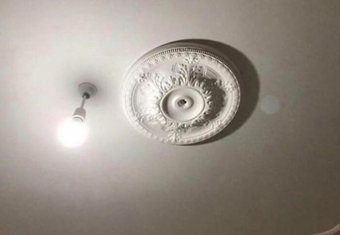 Light fixture installation fail with a bare bulb next to an unused decorative ceiling medallion, showing poor job quality.