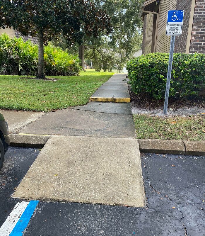Sidewalk ramp for disabled parking that leads directly to a raised curb, showing poor job e*******n.