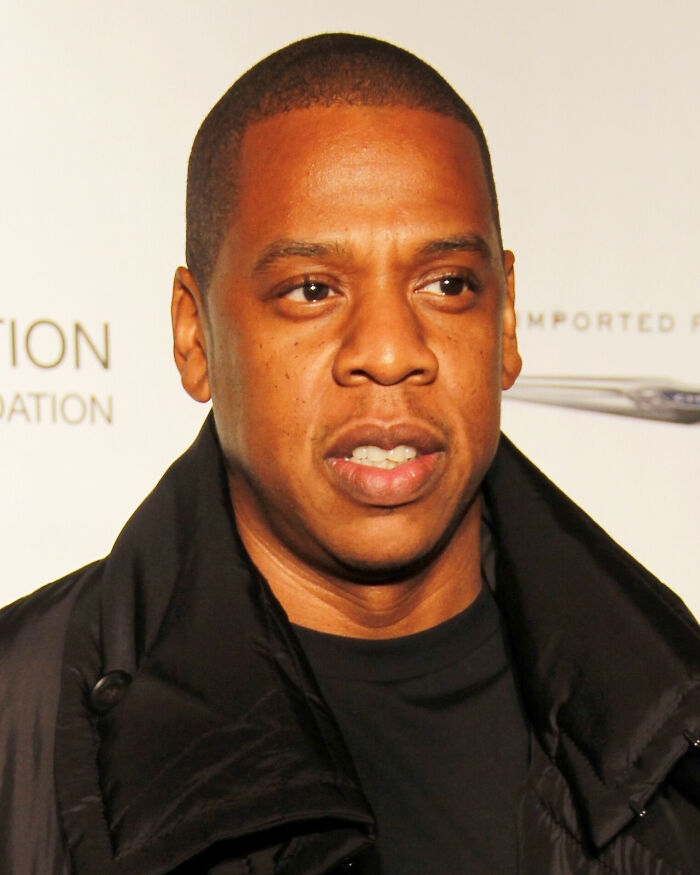 Jay-Z wearing a black jacket, looking off-camera at a music and entertainment event.