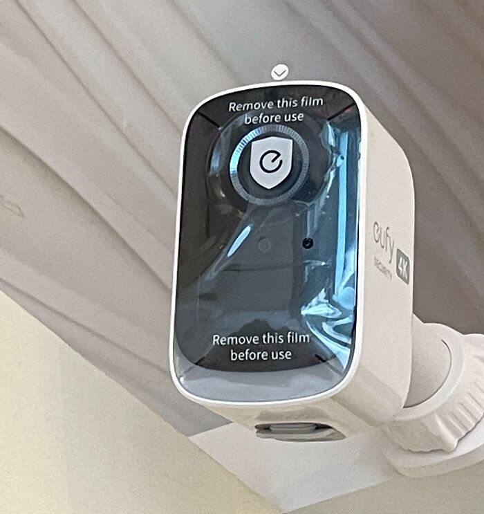 Security camera installed with protective film still on the lens, showing a job done poorly and almost impressive in its oversight.