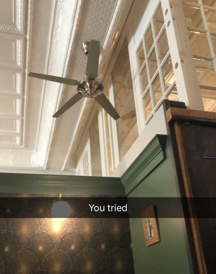 Ceiling fan installed too close to a high window, showing a poor job that is almost impressive.