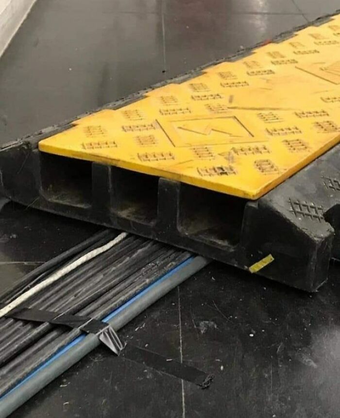 Cable protector poorly installed over uneven floor with exposed cables, showcasing times people did their jobs so poorly.