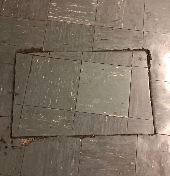 Misaligned floor tiles patched in a way that showcases poor job performance and lack of proper craftsmanship.