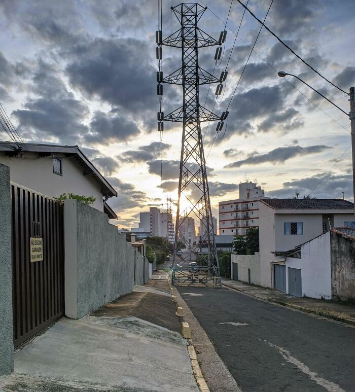 Power lines and a metal tower awkwardly placed in the middle of a narrow street, showcasing poor job e*******n.