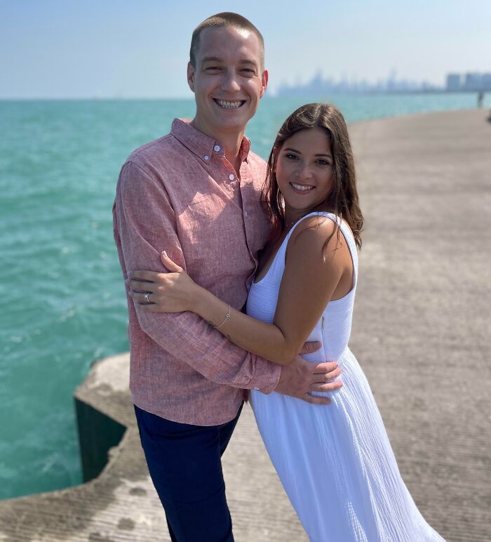 Couple embracing on a pier by the water, a photo so confusing your brain might need a moment to catch up.