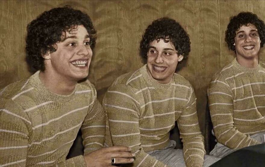 Three identical men with curly hair wearing striped sweaters sitting together, a random picture worth going down a rabbit hole for.
