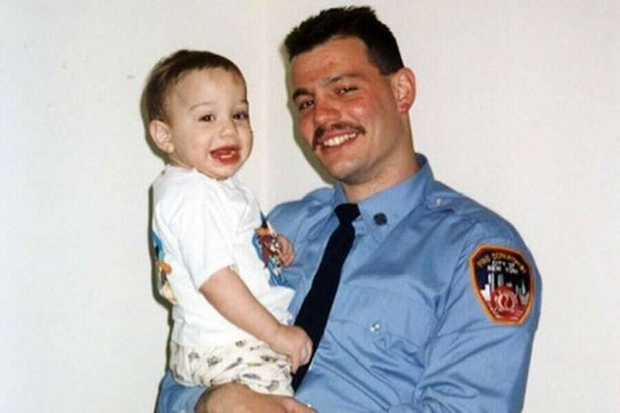 Firefighter in uniform holding smiling toddler, a random picture people say is worth going down a rabbit hole for.