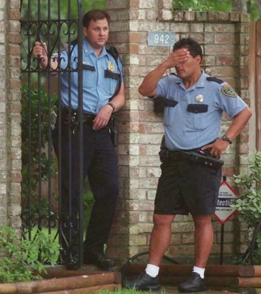 Two police officers in uniform standing by a gate looking stressed in a random pictures rabbit hole moment.