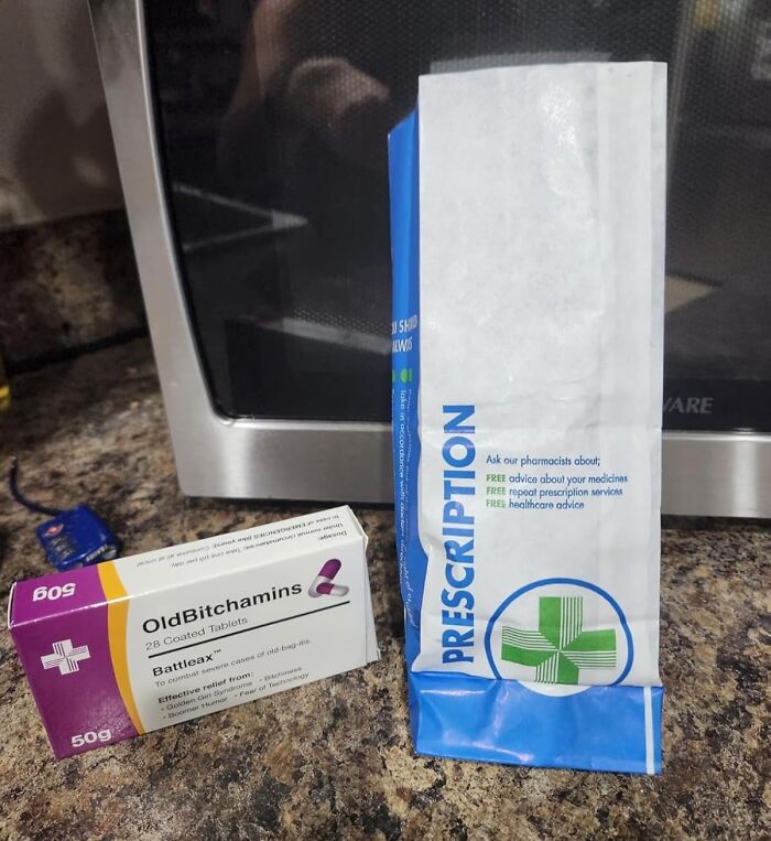 Prescription bag and humorous gag gift pillbox labeled OldBitchamins on a kitchen counter near a microwave.