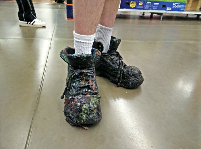 Paint-splattered shoes worn by a person standing on a Walmart store floor, showcasing unusual Walmart store sights.