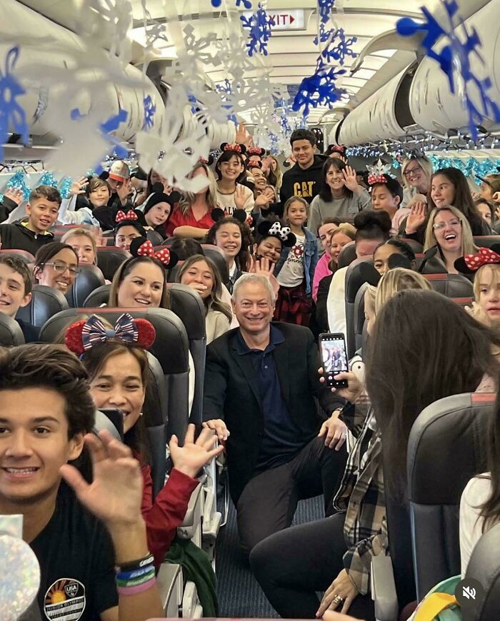 Group of smiling people wearing festive headbands on a decorated plane enjoying a heartwarming moment together.