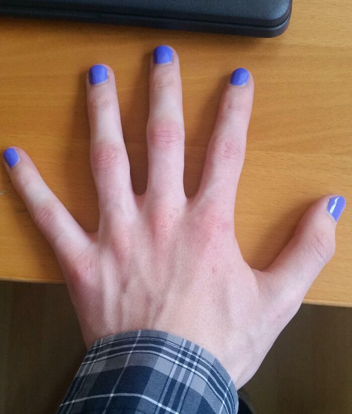 Hand with purple nail polish on all fingers, resting on a wooden desk, symbolizing a leap of faith life decision.