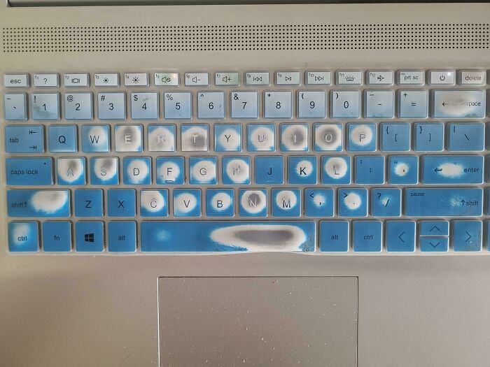 Worn laptop keyboard with faded blue key covers showing heavy daily use in different jobs that make a 9-to-5 bearable.