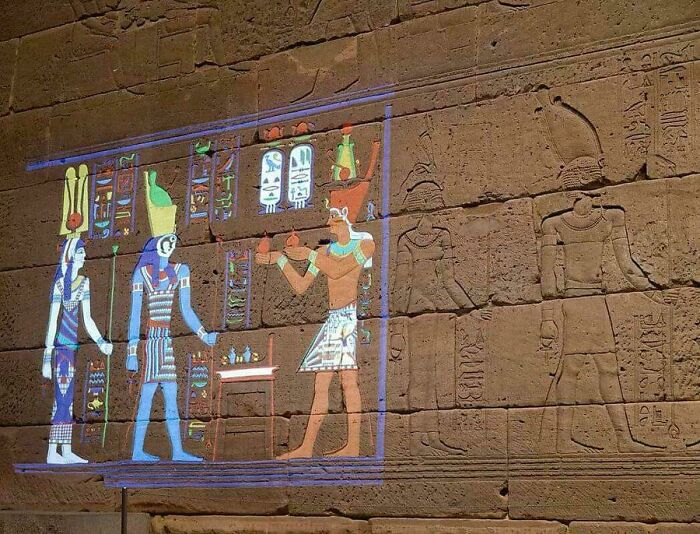 Ancient Egyptian wall carvings and colorful projections showcasing detailed historical scenes and hieroglyphs from ancient Egypt.