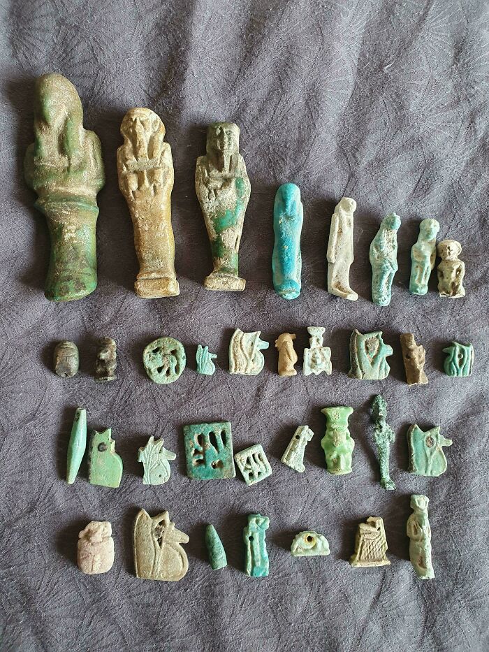 Collection of small ancient Egypt artifacts and figures laid out on fabric, showcasing incredible historical craftsmanship.